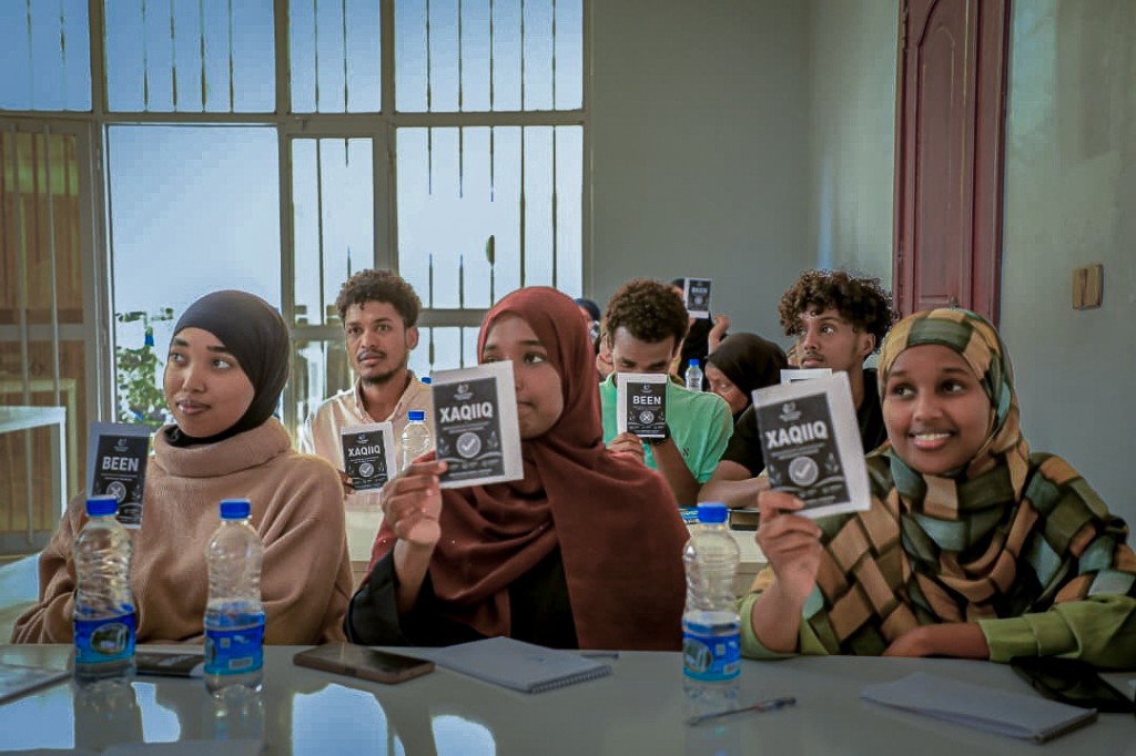 Young people in a Bilis Initiative community workshop holding Xaqiiq and Been cards